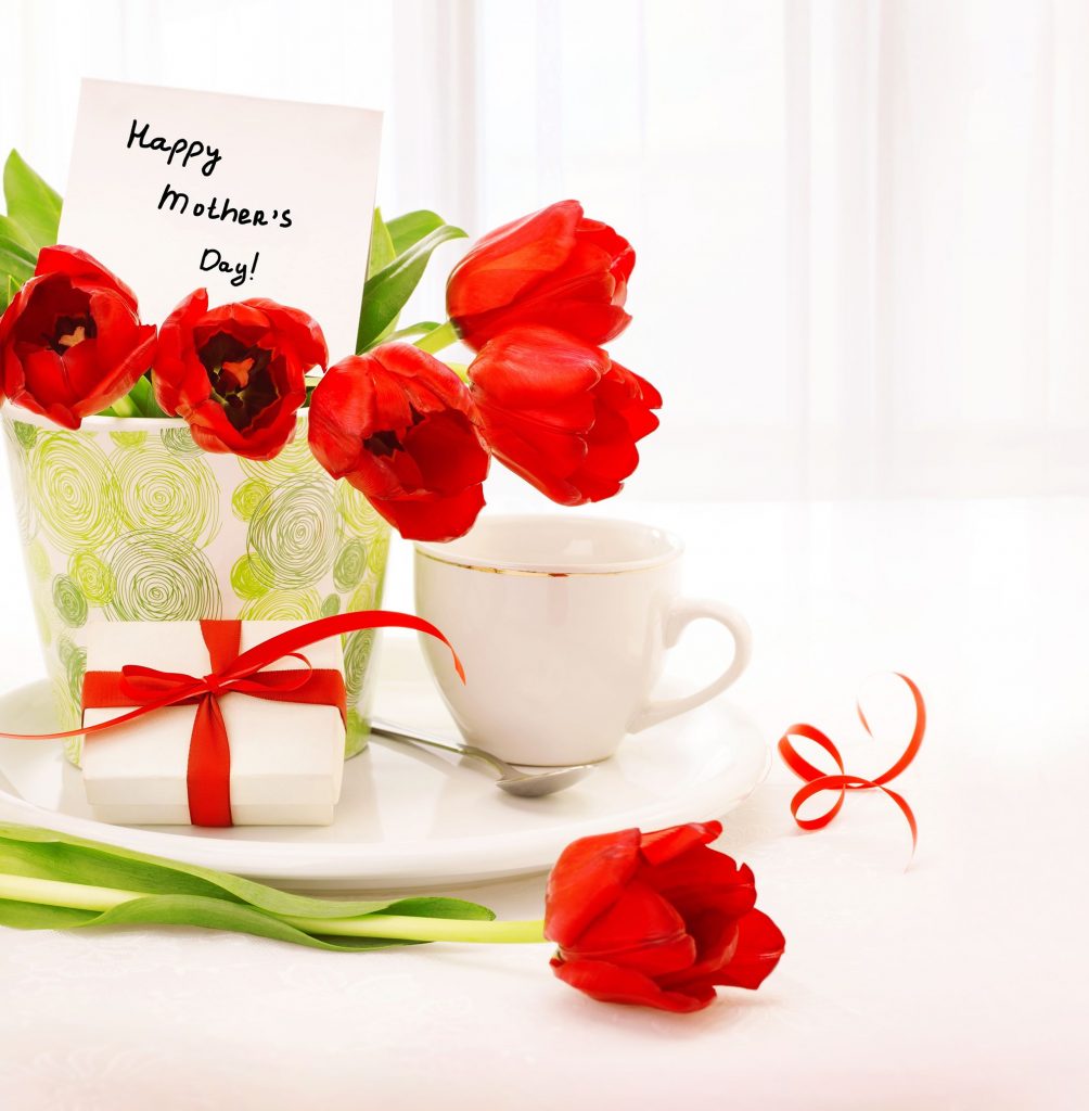 18068314 - picture of beautiful tulips pot with gift box and cup of tea on the table at home